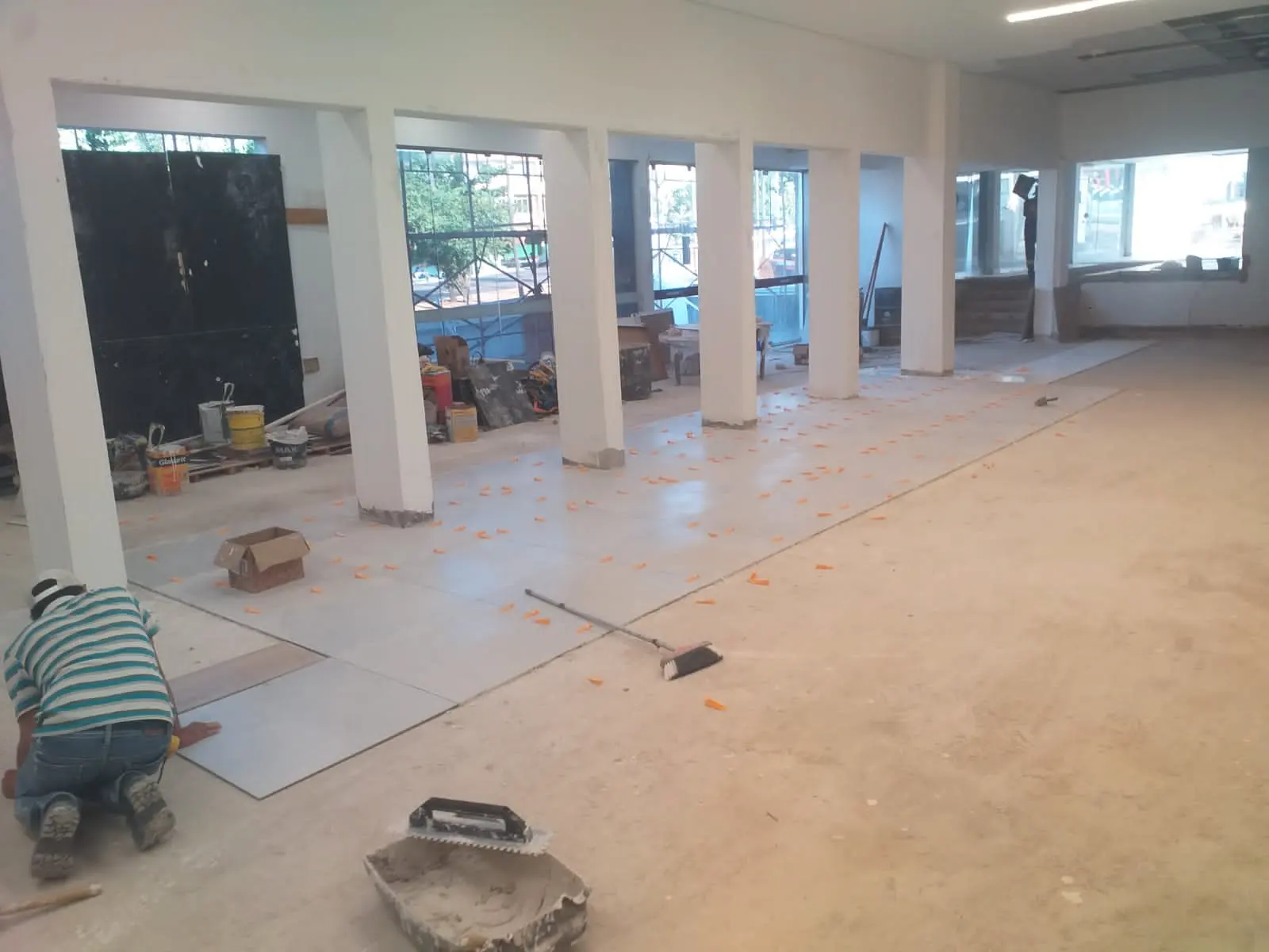 Profissional assentando piso em ambiente comercial em reforma